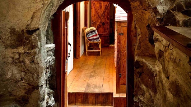 An arched stone doorway leading to a room with wooden flooring and a chair. - Unique Fairytale Farmhouse Near Galway (Corrandulla)
