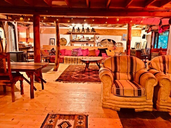 A cozy living room with wooden furniture, a sofa, and a coffee table. There is a fireplace in the background and a dining area with a table and chairs. - Unique Fairytale Farmhouse Near Galway (Corrandulla)