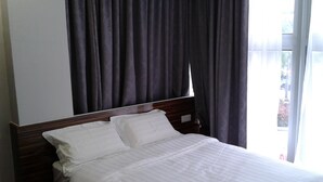 Una habitación de hotel con cama, cortinas y ventana.