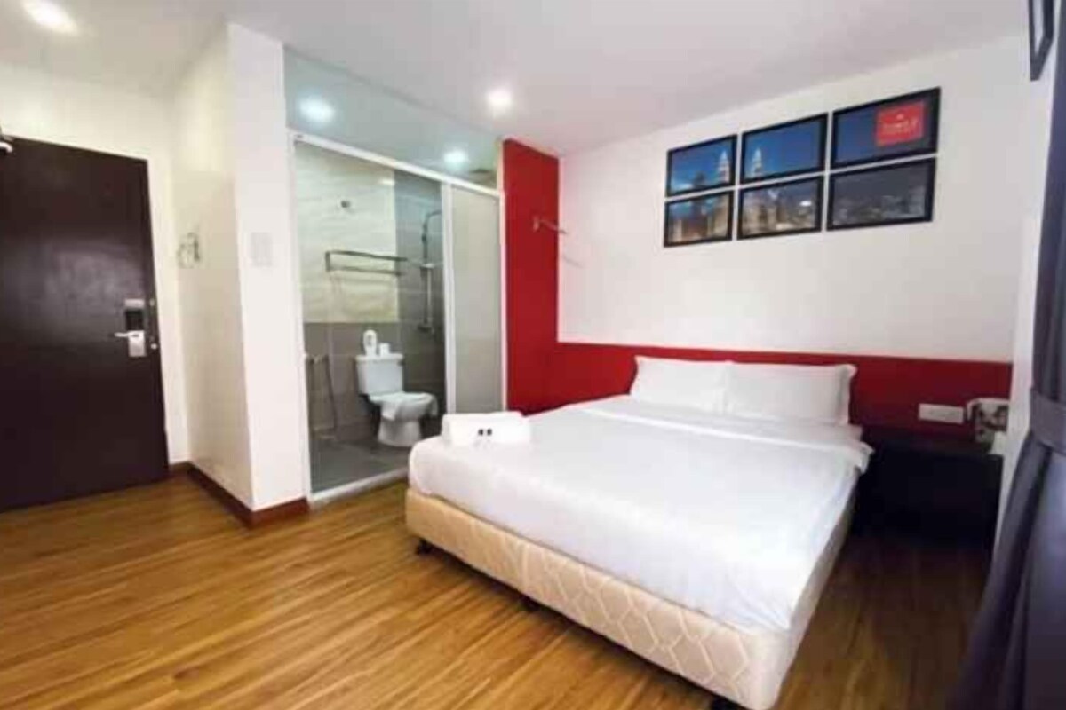 Una habitación de hotel con una cama, ducha y baño.