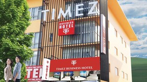 Un moderno edificio de hotel con un letrero destacado que dice 'TIMEZ BUSINESS HOTEL'.
