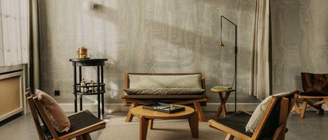 A modern living room with a sofa, two armchairs, a coffee table, and a side table with a lamp.