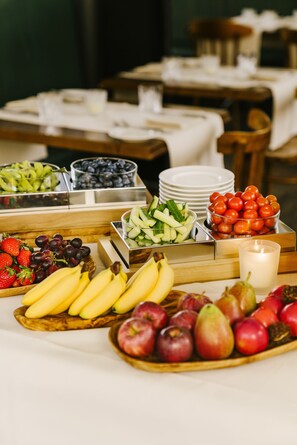 A buffet table with various fruits and a candle.