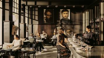 A modern bar with multiple seating areas, including a bar counter and individual tables.