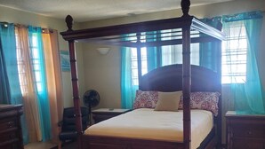 A four-poster bed with a wooden frame, a small wooden table, and a bench in front of it. - Amazing views, relax far away from snow. Fantasy Vacation Planning Available. (St. Thomas)