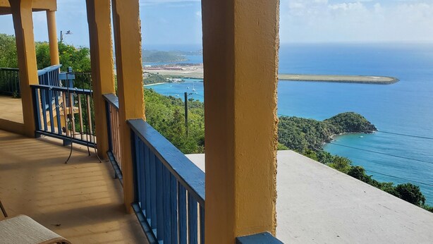A balcony with a view of the ocean and a distant island. - Amazing views, relax far away from snow. Fantasy Vacation Planning Available. (St. Thomas)