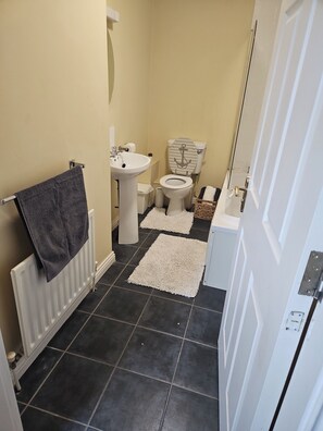 A bathroom with a toilet, sink, and towel rack.