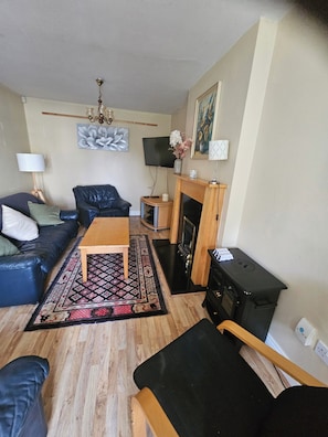 A living room with a sofa, a coffee table, a fireplace, a television, and a chandelier. - The Yellow Bollard Galway (Galway)