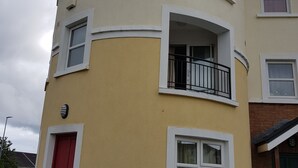 Un immeuble à plusieurs étages, doté d’une façade incurvée, de fenêtres à cadre blanc et d’une porte rouge.