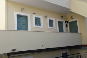 A building facade with multiple windows, some with shutters, and a sign indicating an exit.