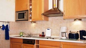 A kitchen with wooden cabinets, a microwave, a toaster, and a coffee maker.