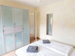 A bedroom with a bed, two towels, a wardrobe, and a mirror.