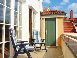 A balcony with two chairs and a green door.