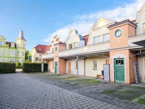 A courtyard with a paved walkway, buildings with distinct architectural styles, and a clear sky.