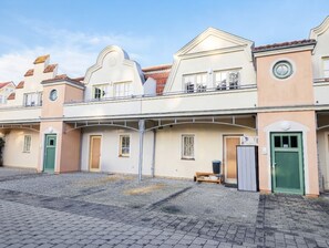 A row of two-story buildings with a consistent architectural style, featuring balconies and a central courtyard.