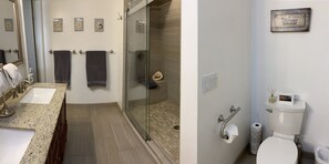 Une salle de bain dotée d’un comptoir en granit, de deux serviettes, d’une cabine de douche en verre, de toilettes avec un porte-serviettes en papier et d’un cadre photo fixé au mur.