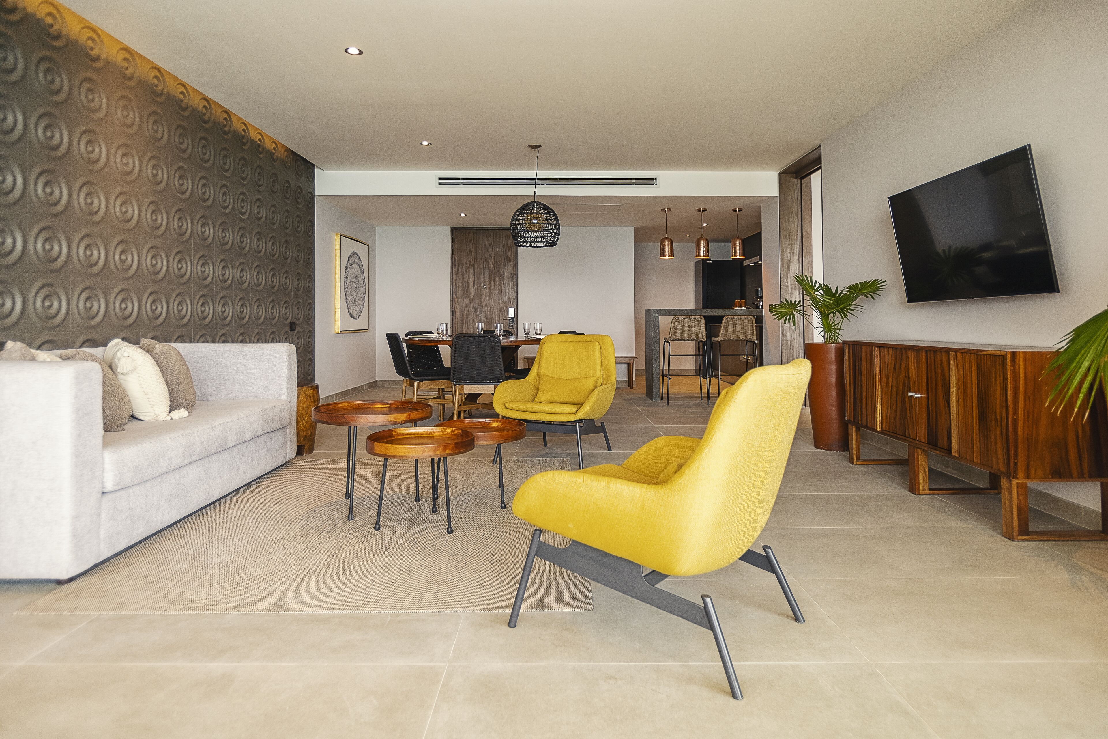 A modern living room with a sofa, yellow armchair, and dining area.