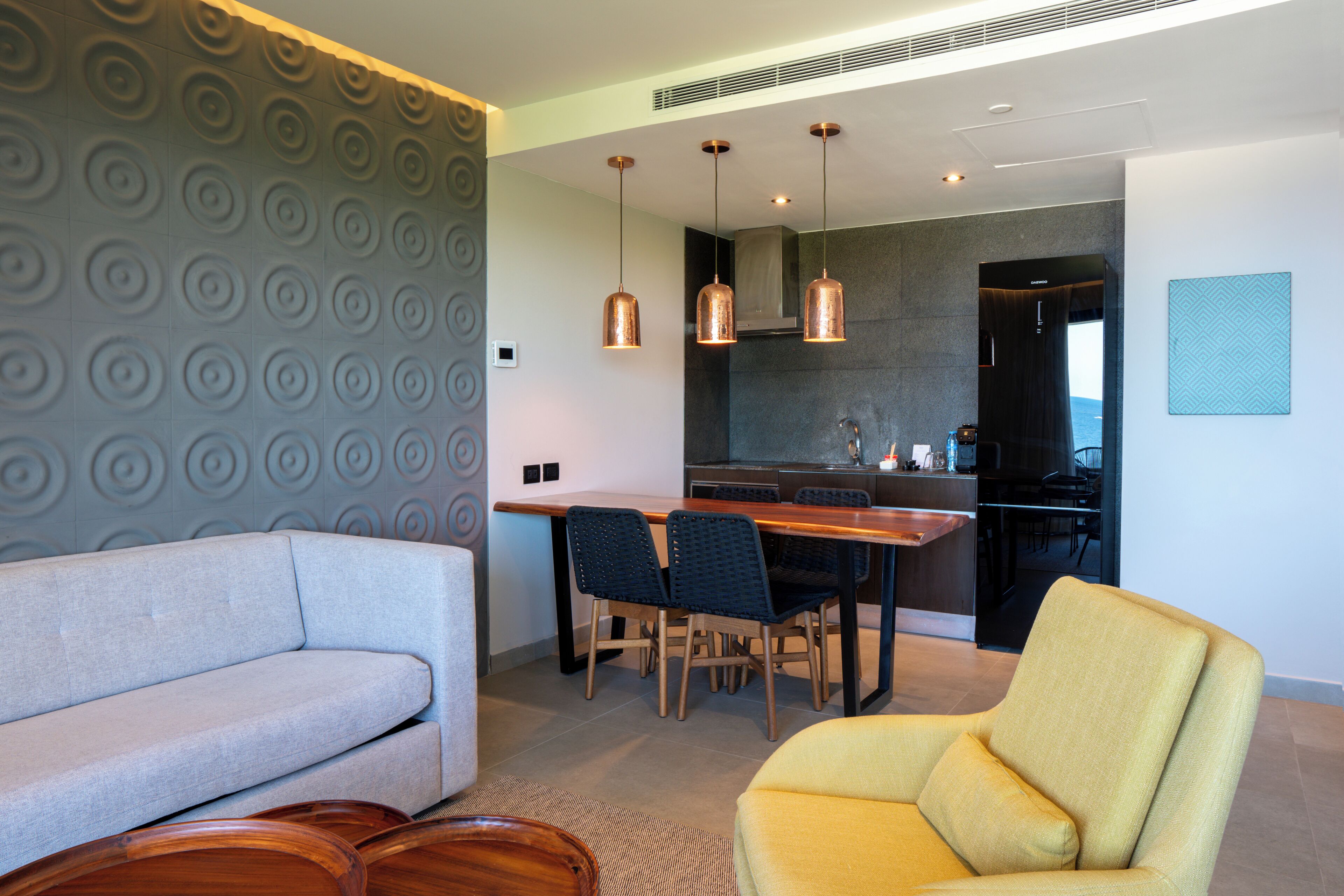 A modern living room with a sofa, a yellow armchair, and a dining area with a table and chairs.