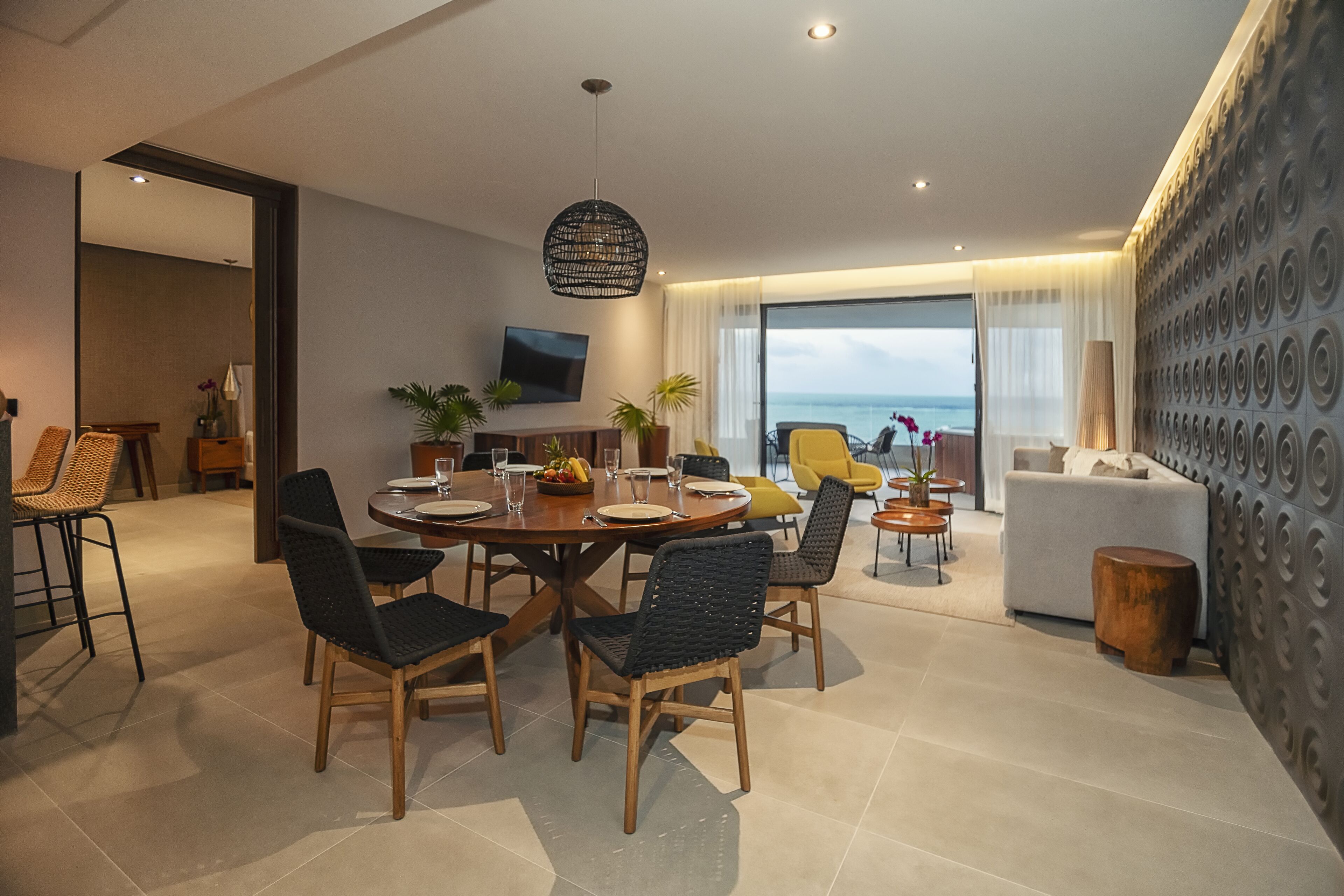A modern dining area with a round table, chairs, and a hanging light fixture.
