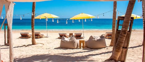 On the beach, white sand, beach cabanas, sun-loungers