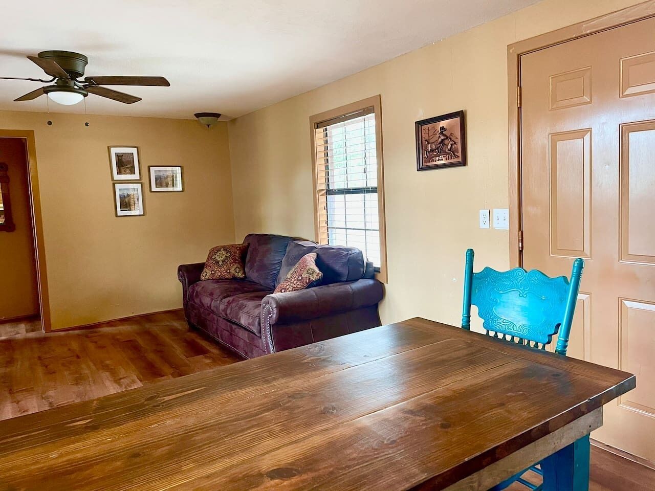 Un coin repas avec une table et des chaises en bois, un canapé et un ventilateur de plafond.