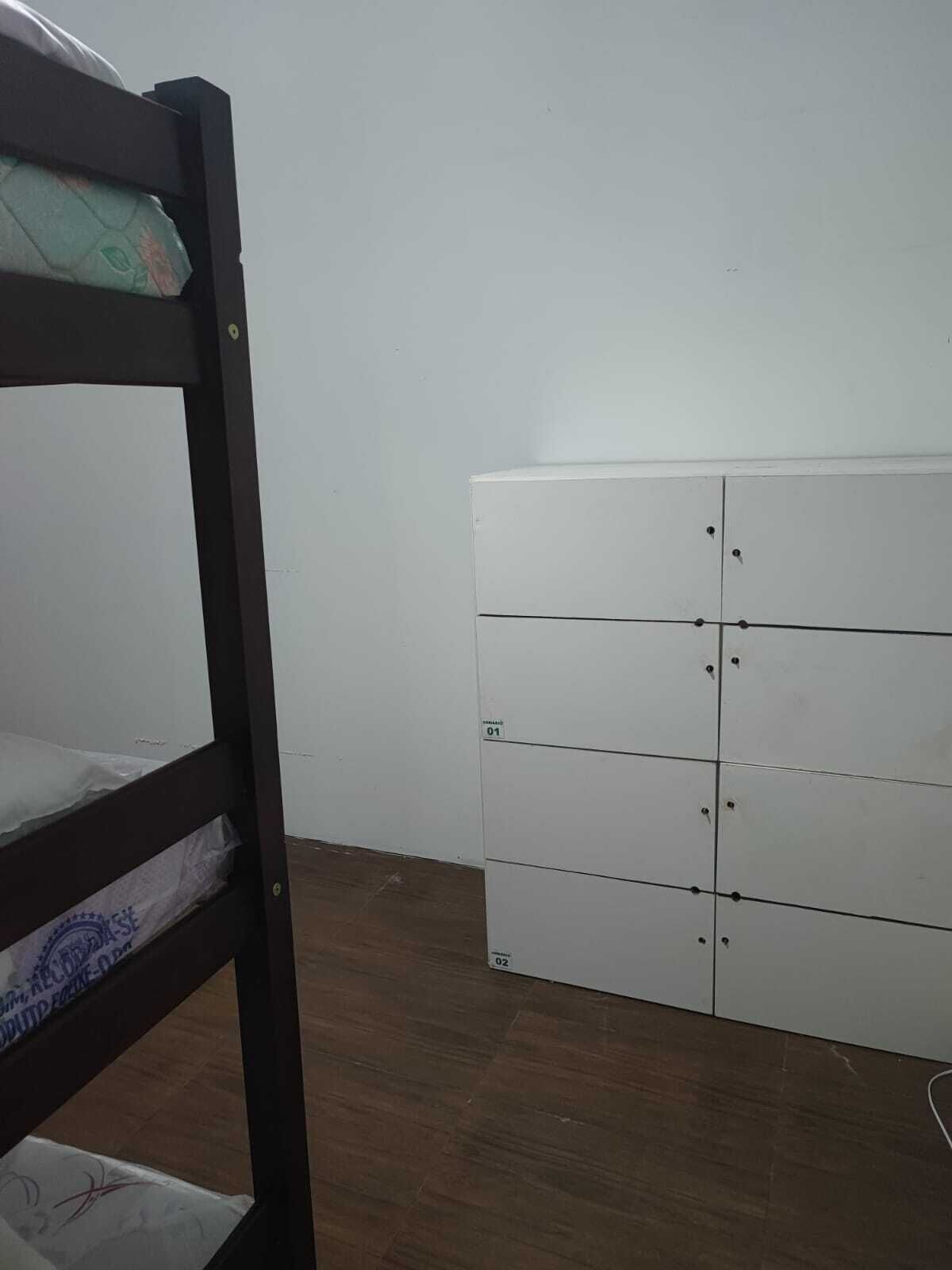 A room with a bunk bed and a white wardrobe with multiple compartments.