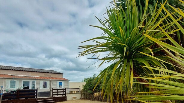 A gravel-covered outdoor area with a building in the background. - REDUCTIONS : TO RENT MOBILE HOME IN LA COTINIERE (Saint-Pierre-d'Oléron)