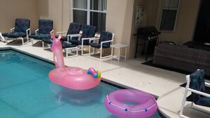 Ett poolområde med solstolar, ett bubbelbad och uppblåsbara leksaker.