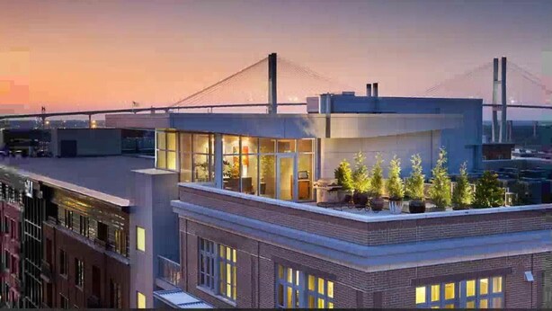A modern building with a rooftop terrace featuring potted plants and a view of a bridge. - Enjoy a Pre-Holiday vacation in Historic Savannah (Savannah)