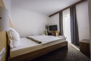 A hotel room with a single bed, a desk with a computer, a TV, and a potted plant. - Guesthouse Vodnik (Cerklje na Gorenjskem)