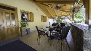 A covered outdoor seating area with wooden furniture, a stone counter, and a potted plant. - Guesthouse Vodnik (Cerklje na Gorenjskem)