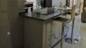 A modern kitchen with a central island, bar stools, and a flat-screen TV. - Amazing one Bedroom Apartment in Amman, Elwebdah 7 (Amman)
