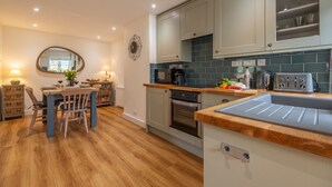 Eine moderne Küche mit hellen Schränken, einer Holz Arbeitsplatte und einem eingebauten Backofen.