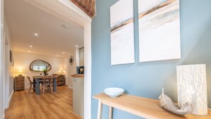 Eine moderne Küche mit Holzboden, einem Essbereich mit Tisch und Stühlen sowie einer hellblauen Wand mit zwei abstrakten Bildern.