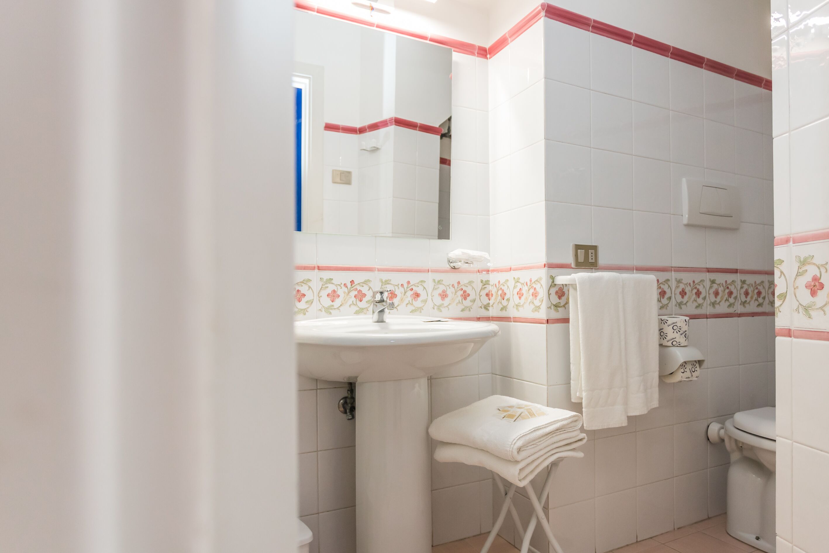 Une salle de bain avec un lavabo blanc, un miroir, des toilettes et un porte-serviettes.