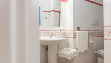 A bathroom with a white sink, a mirror, a toilet, and a towel rack.