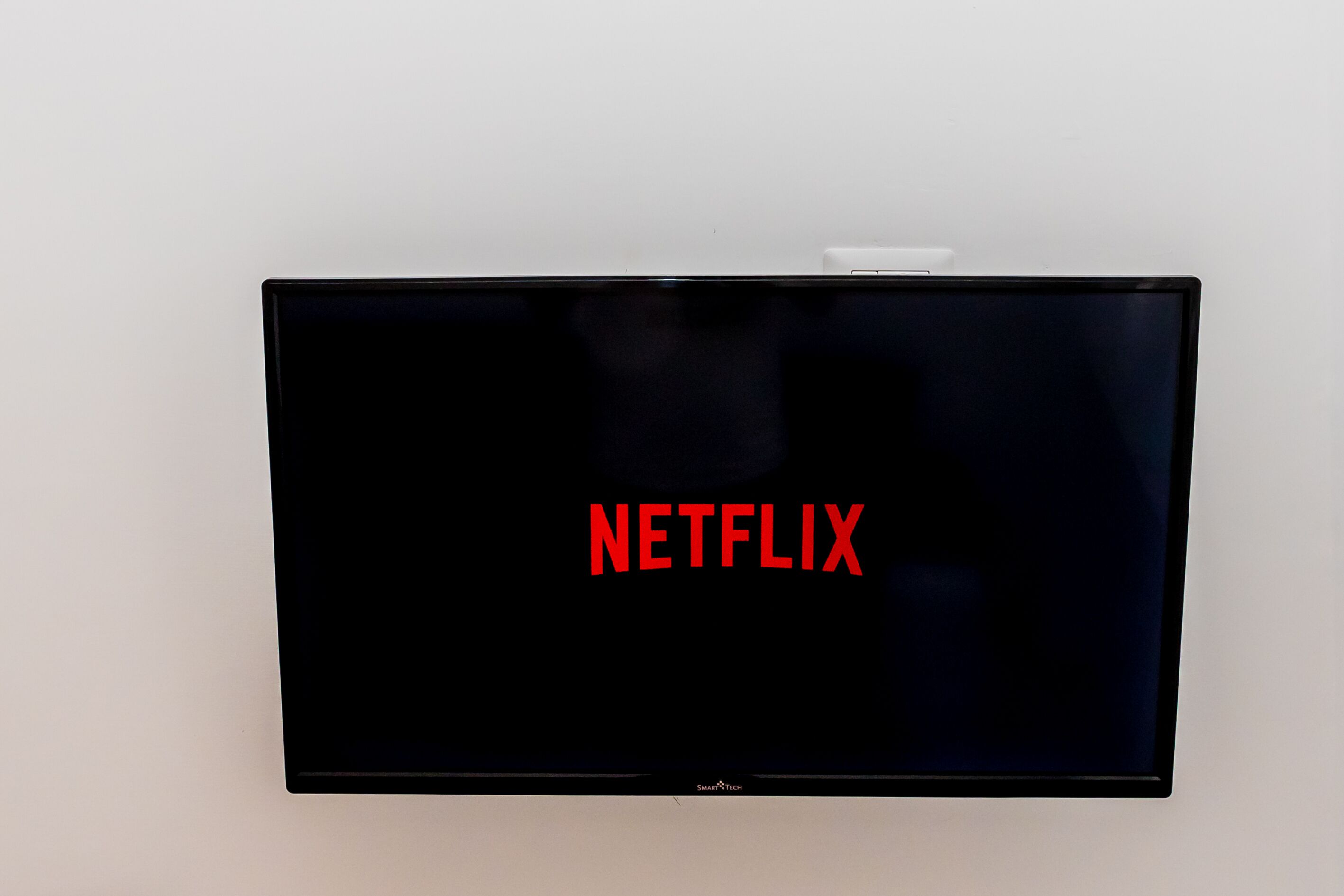 Ein schwarzer Fernseher mit Netflix-Logo an einer weißen Wand.