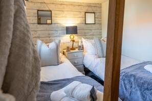 Une chambre avec deux lits, une table de chevet avec une lampe et un miroir au mur.