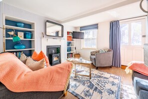 Un salon avec une cheminée, deux canapés, une table basse et une bibliothèque.