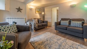 Ein gemütliches Wohnzimmer mit zwei Sofas, einem Couchtisch und einem Kamin.