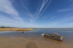 A calm water body with boats, a clear sky, and distant trees. - Bracken Cottage, Brancaster Staithe, Norfolk (Brancaster Staithe)
