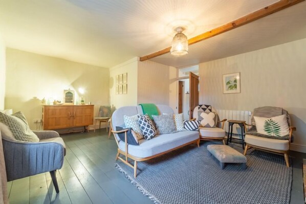 A cozy living room with a sofa, armchairs, a wooden cabinet, and a patterned rug. - Willow Cottage (2), North Creake, Norfolk (North Creake)