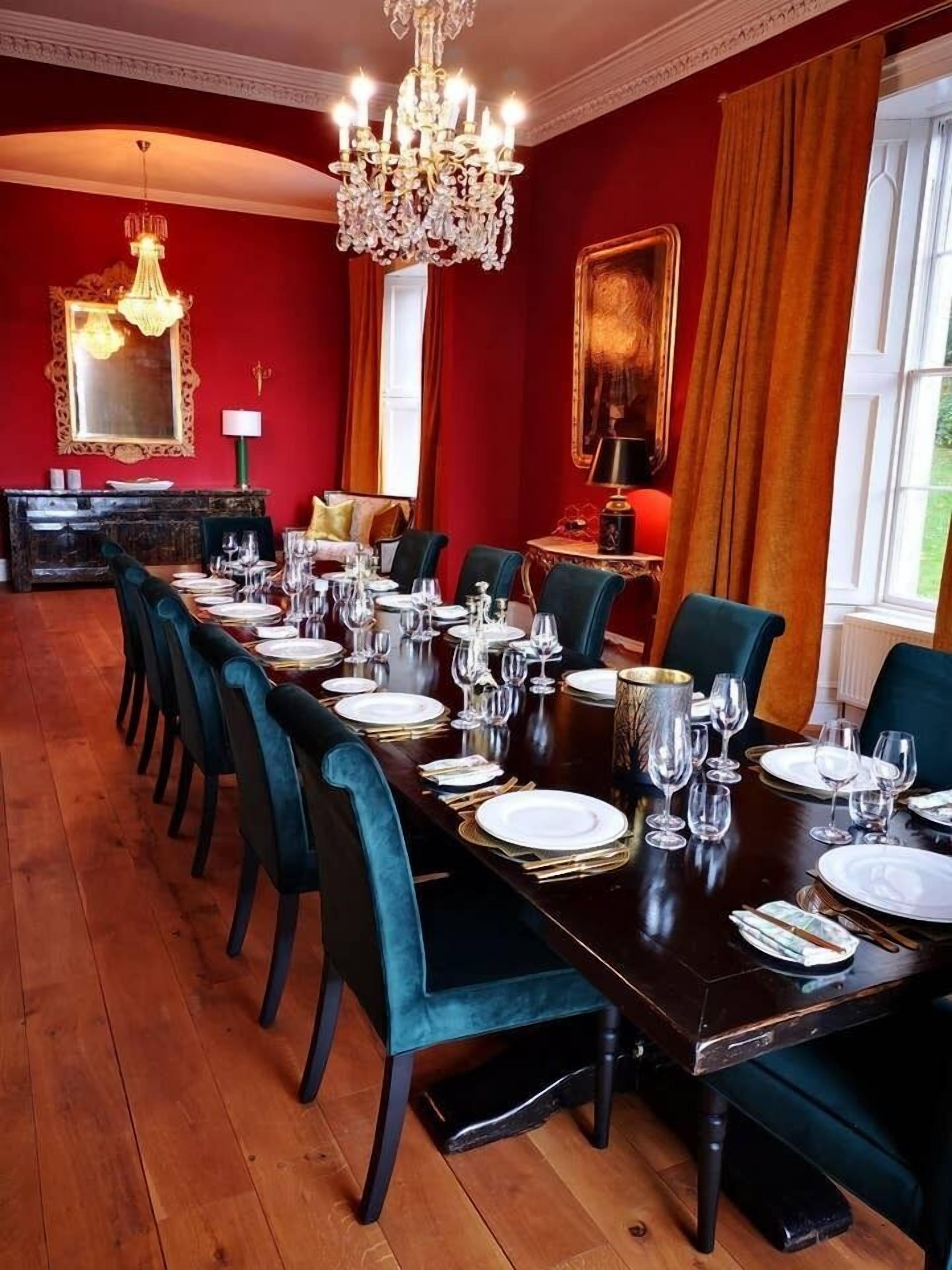 A formal dining room with a long table set for a meal, surrounded by dark chairs.