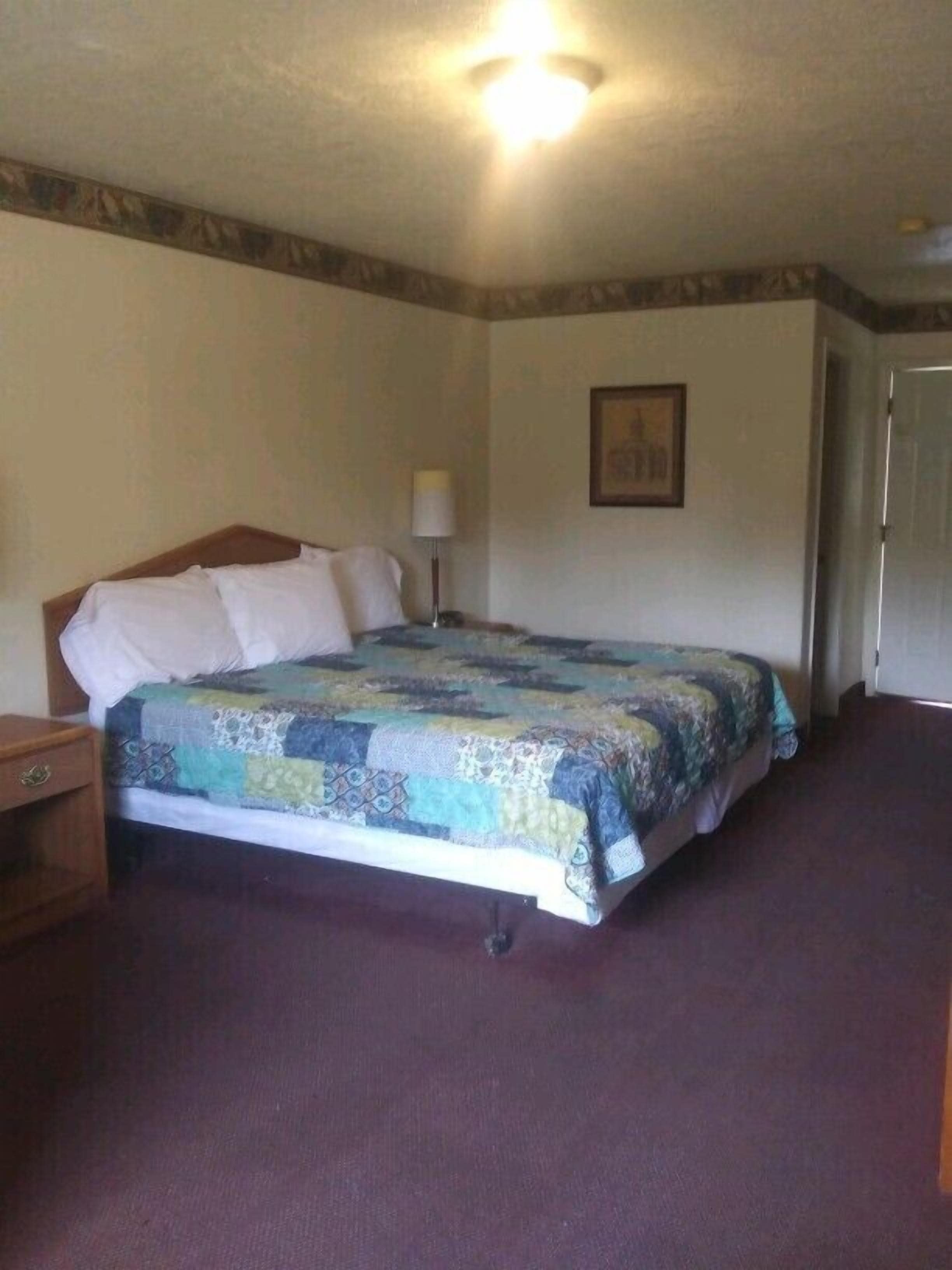 A bedroom with a bed, a nightstand, a lamp, and a door.