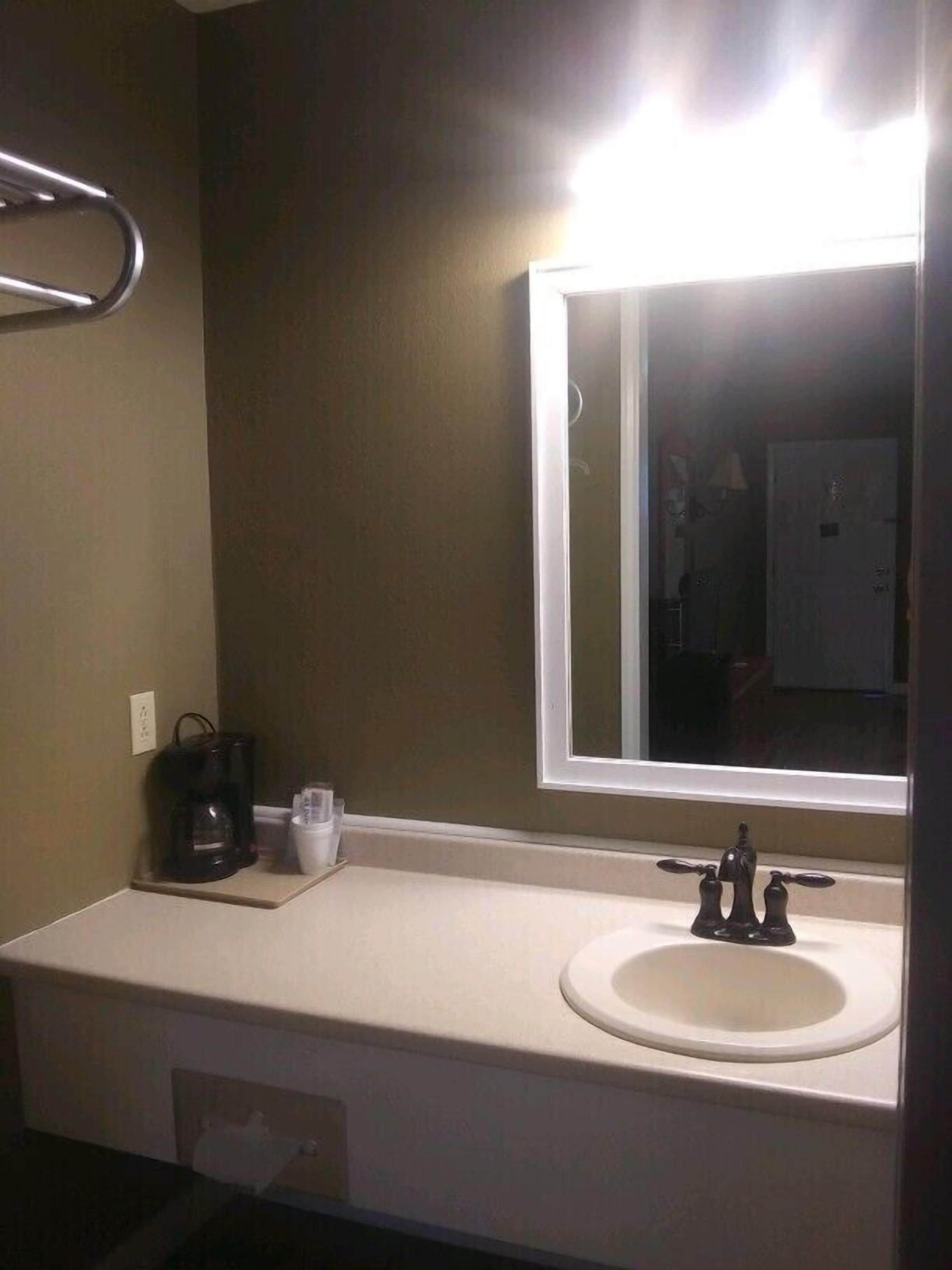A bathroom with a white sink, a mirror, and a towel rack.