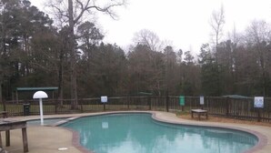 A swimming pool with a wooden deck and a fence. - Whispering Creek Lodging & RV Resort (Newton)