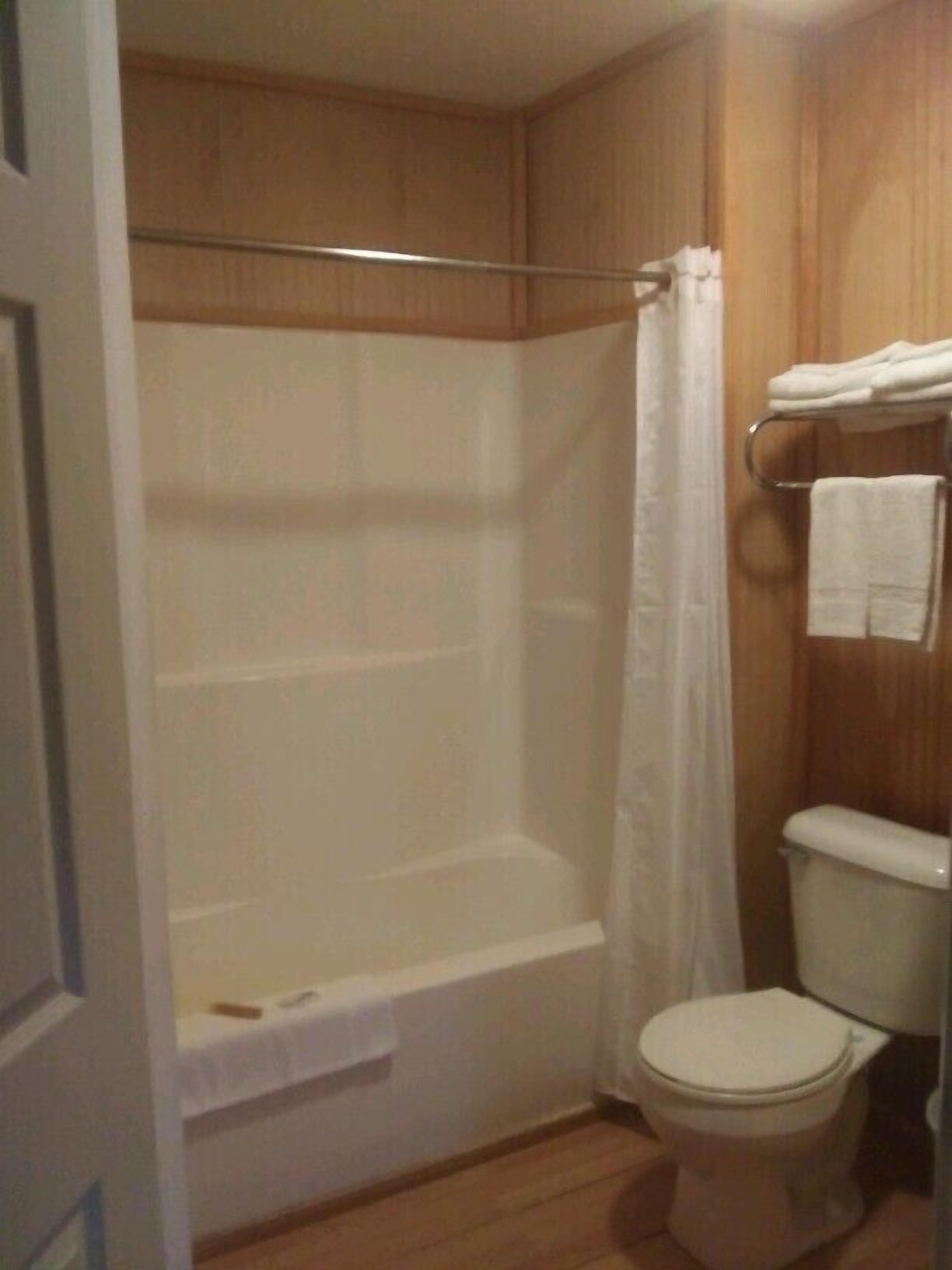 Ein Badezimmer mit Badewanne, Duschvorhang, Toilette und Handtuchhalter.