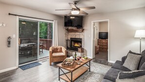 A living room with a fireplace, a ceiling fan, a television, and a sofa.