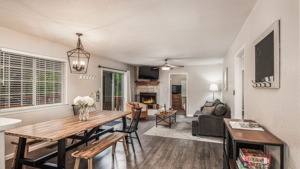 A spacious living area with a wooden dining table, black chairs, a sofa, and a bookshelf.