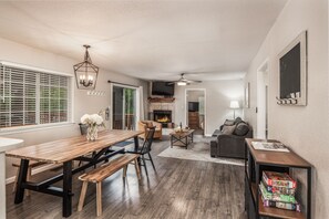A spacious living area with a wooden dining table, black chairs, a sofa, and a bookshelf. - Midtown Modern Mountain Getaway (Ruidoso)